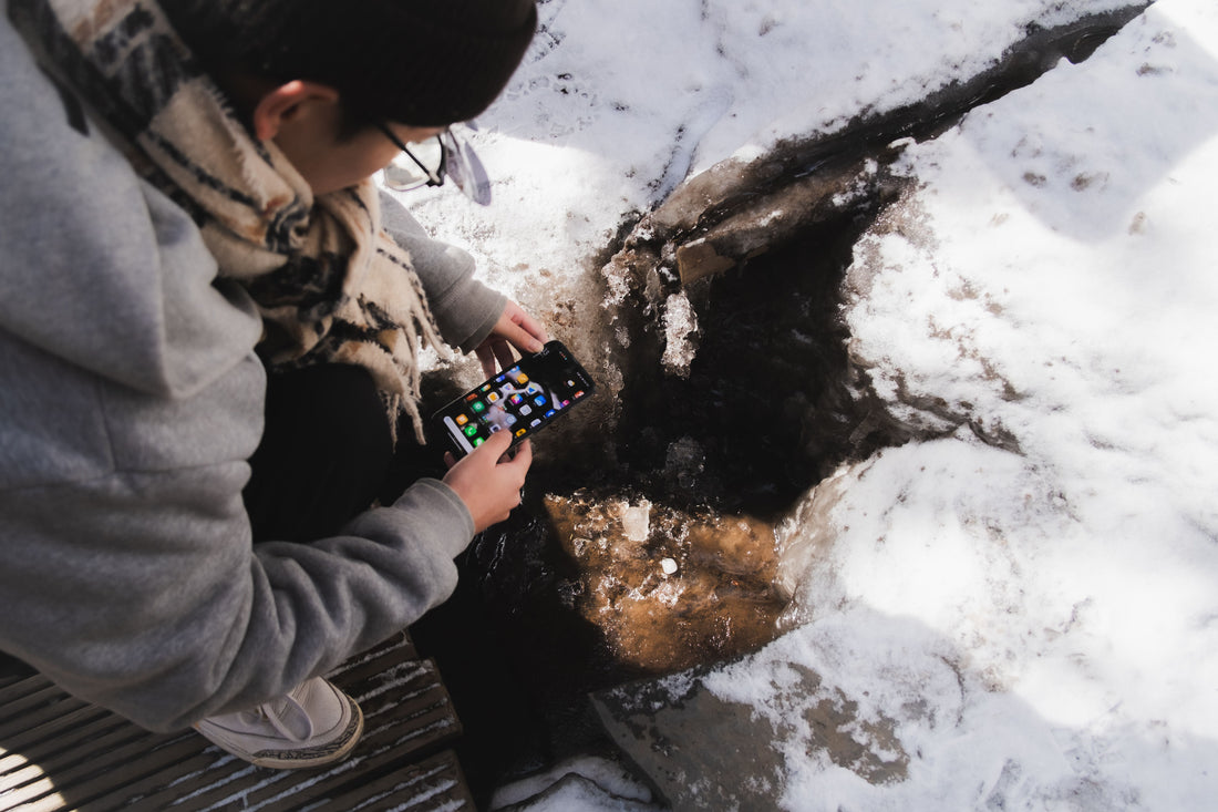 Shopper checking snow conditions on a phone outdoors, the kind of weather that triggers a free if it snows promotion