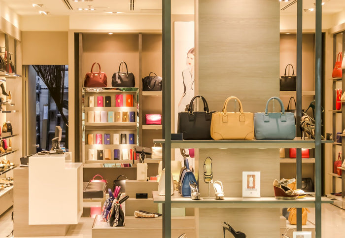 Luxury boutique interior with designer handbags and shoes on lit display shelves