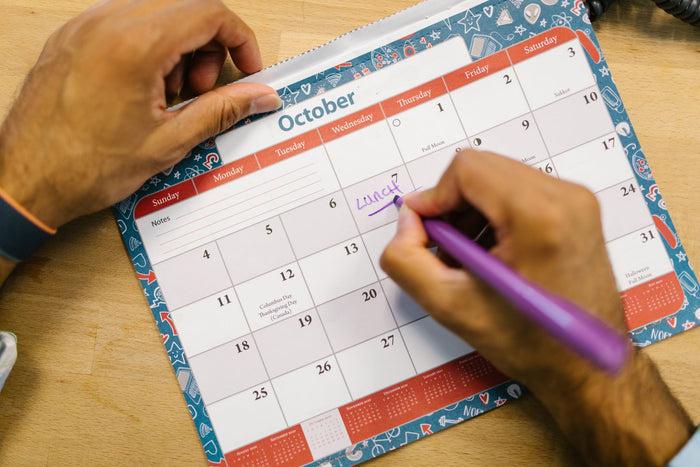 Marking dates on an October desk calendar while planning a Q4 marketing calendar