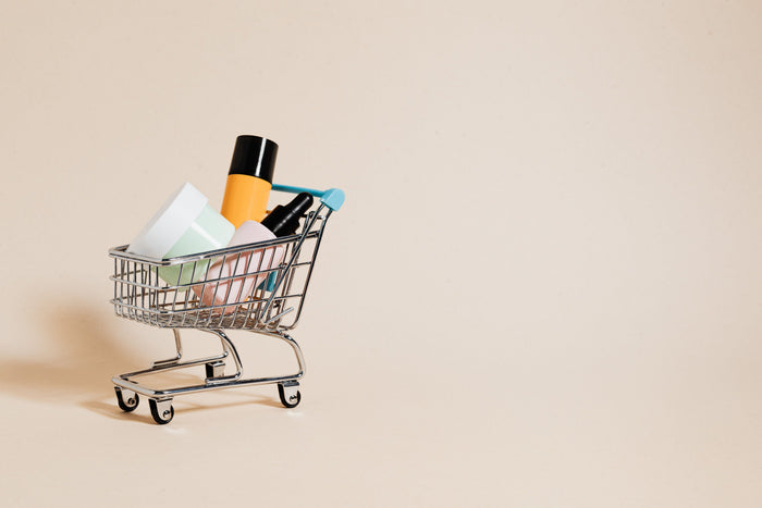 Mini shopping cart filled with beauty products on a beige background, representing higher order value without discounts.